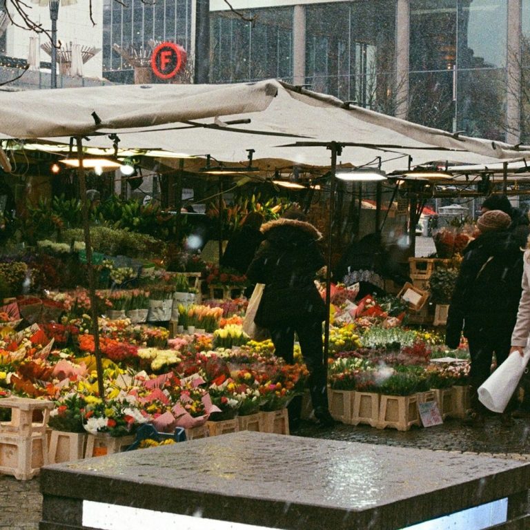 Marktstände auf einem Markt mit Menschen, die einkaufen.